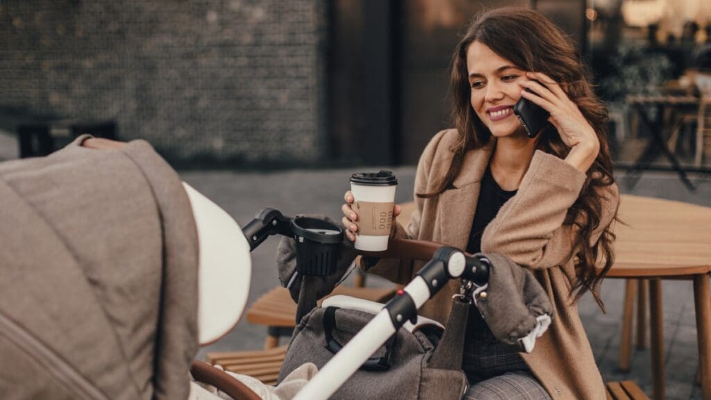 Mother sitting at an outdoor café smiling at her baby in a stroller at The Shops at Marley Park.