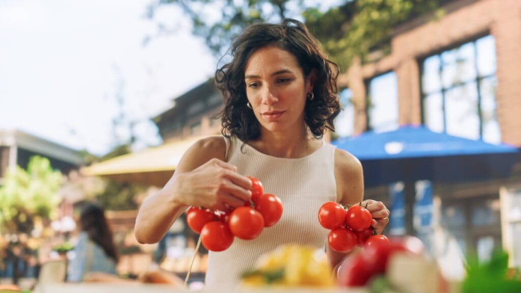 Woman shopping for fresh tomatoes at a farmers market in Marley Park.
